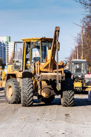 A heavy front loader transports earth in a bucket and grades the road. Road repair in the center of...