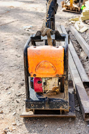 Vibratory rammer with vibrating plate on a construction site. Compaction of soil for further...