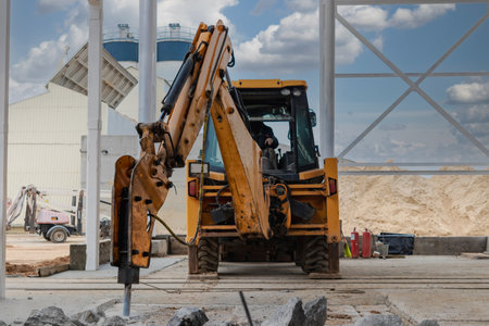 Professional demolition of reinforced concrete structures with an industrial hydraulic hammer with an excavator. Dismantling the concrete floor in the production area. Debris and crumbs of concreteの写真素材
