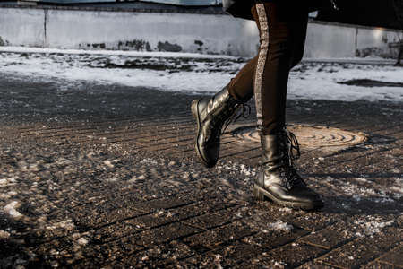 People walk on a slippery road made of melted ice. View of the legs of a man walking on an icy pavement. Winter road in the city. Injury after a fall on an icy roadの写真素材