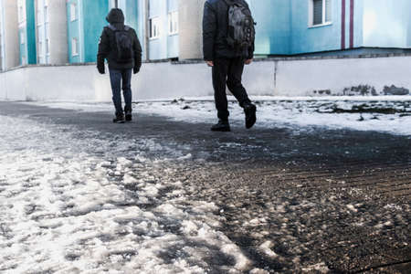 People walk on a slippery road made of melted ice. View of the legs of a man walking on an icy pavement. Winter road in the city. Injury after a fall on an icy roadの写真素材