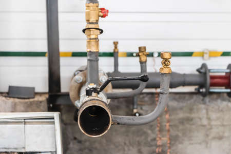 Industrial valve on a gas or heating pipe. Installation of a heating unit in a production room. Metal pipes for heatingの写真素材