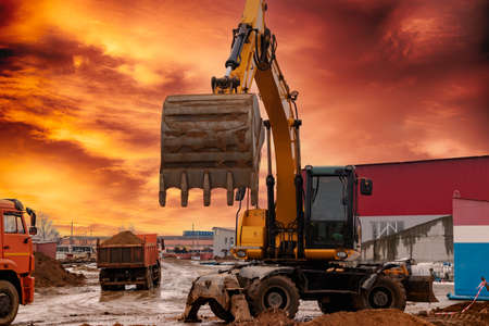 An excavator loads soil or sand into a dump truck. Pit development. Earthworks with the help of heavy construction equipmentの写真素材