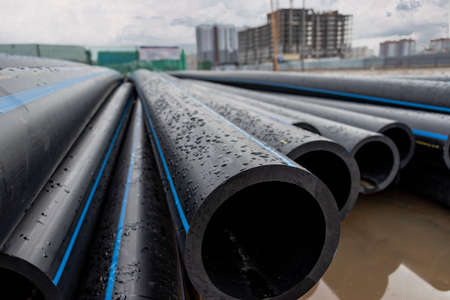 Water pipes for drinking water supply lie on the construction site. Preparation for earthworks for laying an underground pipeline. Modern water supply systems for a residential cityの写真素材