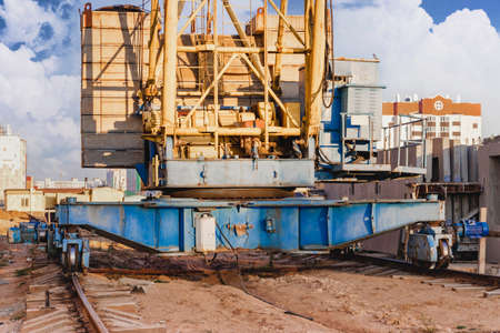 Tower crane on rails close-up against the background of the cloudy sky. Modern housing construction....