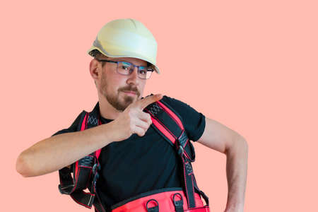 Positive friendly bearded male builder in overalls and safety hardhat and goggles looking at the camera over isolated backgroundの写真素材