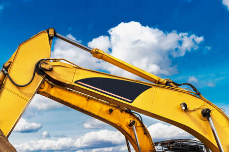 Arrow of a powerful excavator against a blue cloudy sky. Construction equipment for earthworksの写真素材