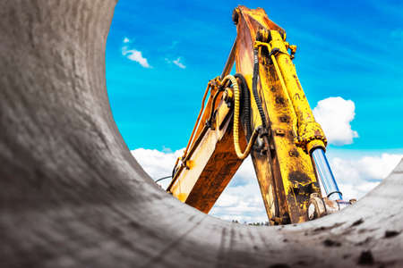 Heavy excavator at the construction site. View of the excavator through the iron pipe. Construction equipment for earthworks. Quarry excavatorの素材 [FY310186613412]