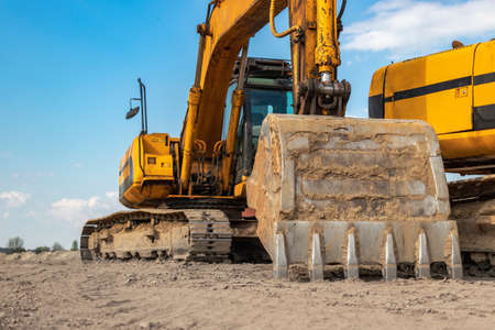 Powerful excavators at a construction site against a blue cloudy sky. earthmoving construction...