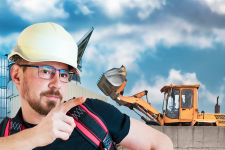 A male builder in a white hard hat against a blurred background of a construction site with a blue...