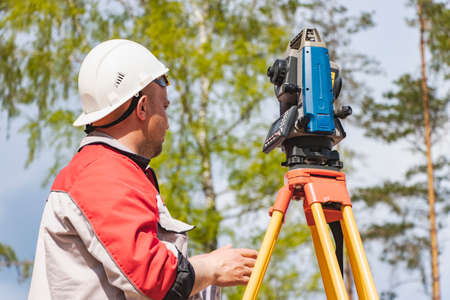 Construction of a residential area. geodetic stakeout. Surveyor at a large construction site. A man with a tachometer during work. Makshaderの写真素材