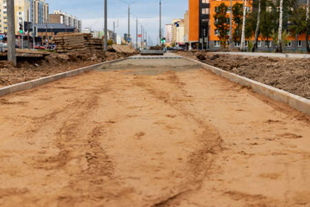 Pavement repair and laying of paving slabs on the walkway, installation of curbs and curbstones. Laying paving slabs in the pedestrian zone of the city, sand filling. Road tiles and curbsの写真素材