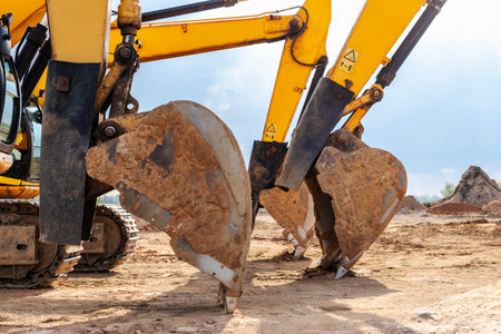 Powerful excavators at a construction site against a cloudy evening sky. earth moving construction equipment. Lots of excavatorsの写真素材