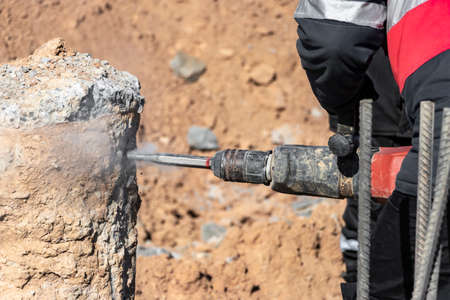 A worker with a jackhammer breaks concrete piles. Felling the pile head with a hand tool....
