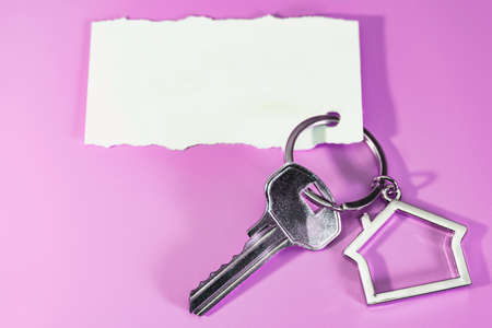 The concept of mortgage, sale and rental of housing and real estate. Mortgage credit lending. Keychain in the shape of a house with a key on a beige background. banner formatの写真素材