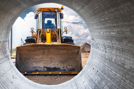 View from the pipe as a bulldozer or loader moves the earth at the construction site. An earthmoving...