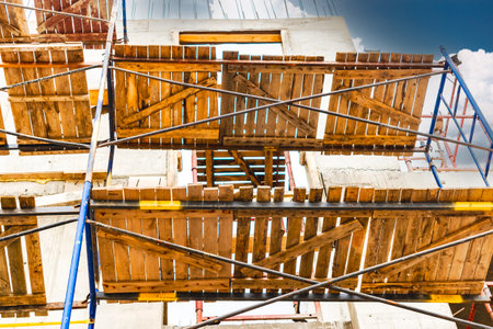 Construction of a new monolithic reinforced concrete house. Scaffolding on the facade of a building under construction. Working at height on a construction siteの写真素材