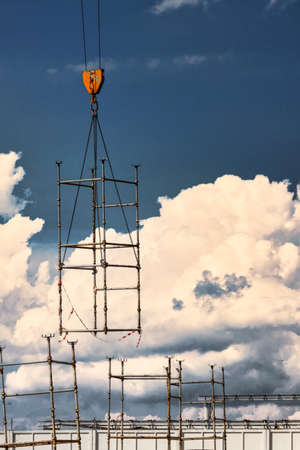 A crane lifts formwork elements at a construction site against a blue sky. Monolithic concrete works