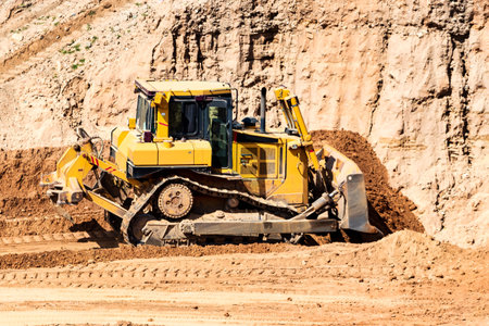 A powerful bulldozer in a sand pit is planning a site. Extraction of sand in an open pit. natural building materialsの写真素材