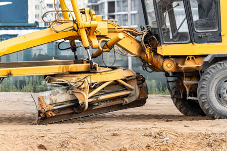 Road grader at the construction site. Powerful construction machine for ground leveling and...