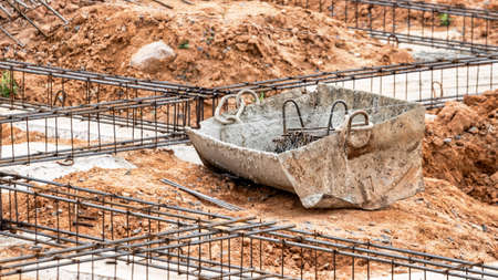 Reinforced concrete foundation of a modern monolithic residential building. Prepared formwork with reinforcing mesh for pouring concrete. Dirt and clay at the construction siteの写真素材
