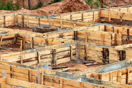 Reinforced concrete foundation of a modern monolithic residential building. Prepared formwork with reinforcing mesh for pouring concrete. Dirt and clay at the construction siteの写真素材