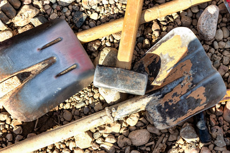 Working construction tool on gravel. Paws and a sledgehammer on the ground. industrial background. Hand tool of a worker at a construction siteの写真素材
