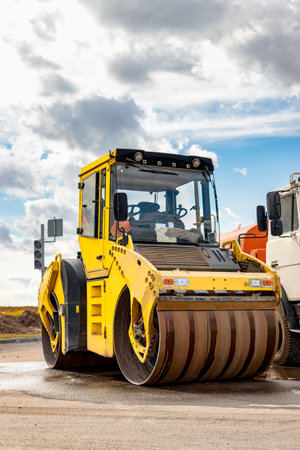 Vibratory road roller lays asphalt on a new road under construction. Close-up of the work of road...