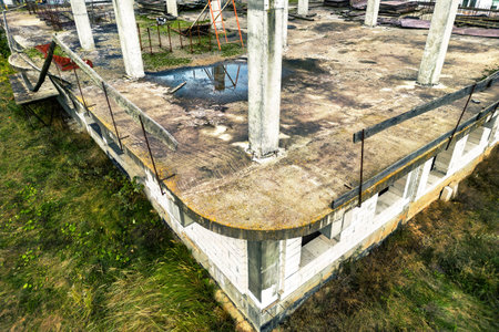 Abandoned construction site of a reinforced concrete monolithic house. Abandoned building materials. Stop financing construction. Shooting from a droneの写真素材