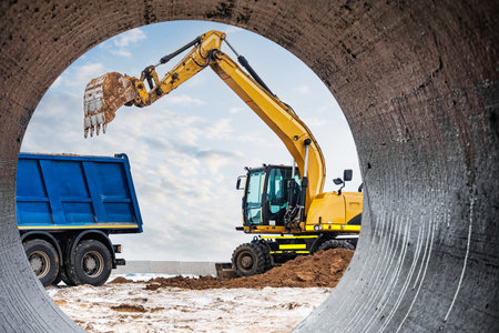 An excavator loads soil or sand into a dump truck. Pit development. Earthworks with the help of...