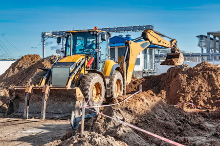 A universal excavator is working on a construction site against a cloudy sky. Earthworks at a construction site. Modern earthmoving equipment. The contractor is doing construction workの写真素材