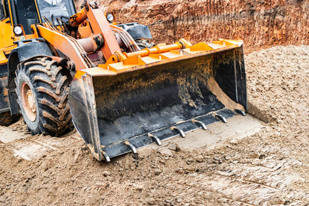 Powerful wheel loader or bulldozer working on a quarry or construction site. Close-up of earthworks. Powerful modern equipment for earthworksの写真素材