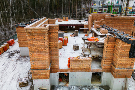 Top view of the construction site. Construction of a red brick house. building in winter. Detailed shot of the construction site. Snow on the construction siteの写真素材