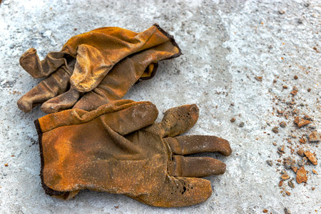 Leather construction gloves on the concrete surface of the foundation. Old worker's gloves on a vintage background. Remedy protection.の写真素材