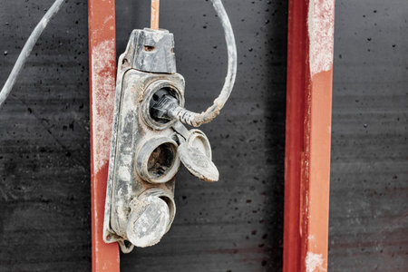 Extension cord, electrical socket, power cord old and damaged on the construction site outside. Extremely dangerous, unsafe to use. should be replaced. unsafe workplaceの写真素材