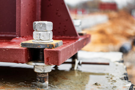 Installation of a metal column for an industrial building. Mounting bolts close-up. Connection of a...
