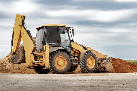 Powerful wheel loader or bulldozer at the construction site. Loader transport sand in a storage...