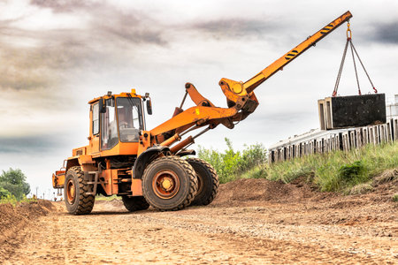 Powerful wheel loader for transporting bulky goods on the construction site. Transportation of concrete products. Transportation and movement of heavy long cargoesの写真素材