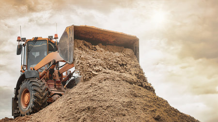 Powerful wheel loader or bulldozer working on a quarry or construction site. Loader with a full...
