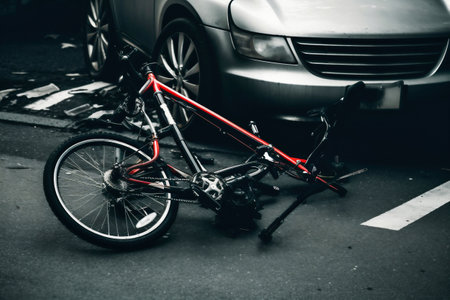 Groceries and broken bike on pedestrian crossing after collision with a car. Car accident on the street, hit by a cyclist after a collision. Violation of traffic rulesの素材