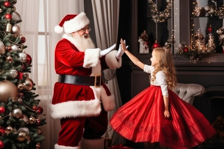 A little girl standing next to a santa clauseの素材