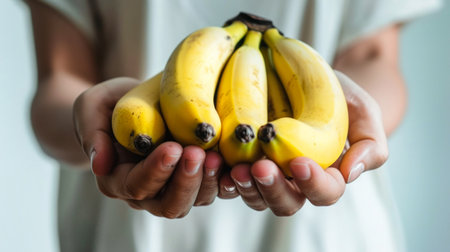 A person holding a bunch of bananas tightly in their hands.の素材