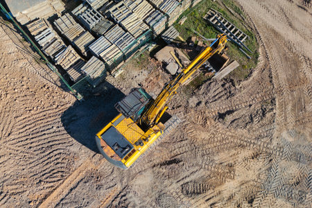 Aerial view of excavator working in quarry or construction site. Industrial top view background concept. A mining excavator is digging a pit. Rental of construction equipment. Contractorの写真素材