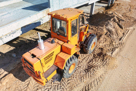 A yellow tractor is parked in rough dirt, ready for construction work. Construction excavator or loader.の写真素材