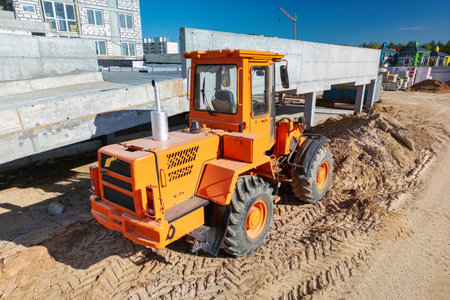 An orange tractor is stationary in a dirt field or construction site. Construction excavator or loader.の写真素材
