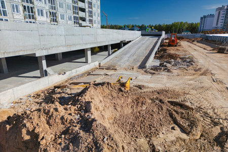 A construction site with workers and machinery in front of a massive building, showing ongoing construction activity.の写真素材