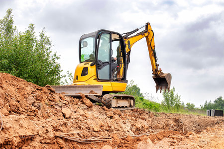 A excavator actively digging through a mound of soil and dirt, creating a path and clearing the area.の写真素材