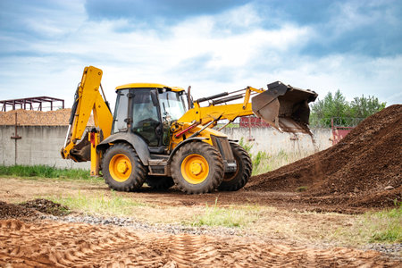 A bulldozer or a loader is actively dumping dirt into a growing pile at a construction site.の写真素材