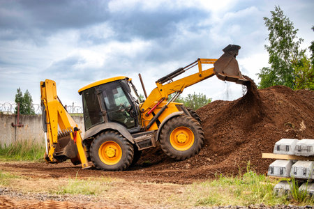 A bulldozer or a loader actively digging into a large pile of dirt at a construction site.の写真素材