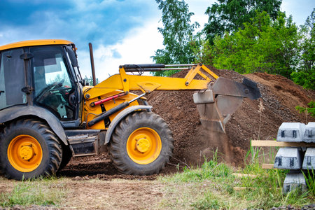A bulldozer or a loader is actively digging into a large pile of dirt, moving the earth to clear or level the area.の写真素材